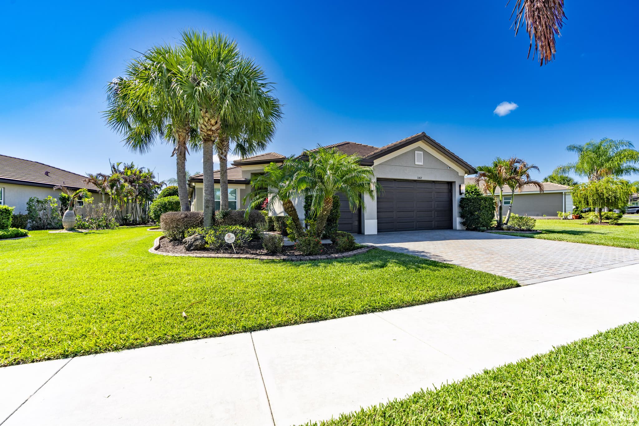 Front elevation of 11402 SW Half Moon Lake Ln with tropical landscaping