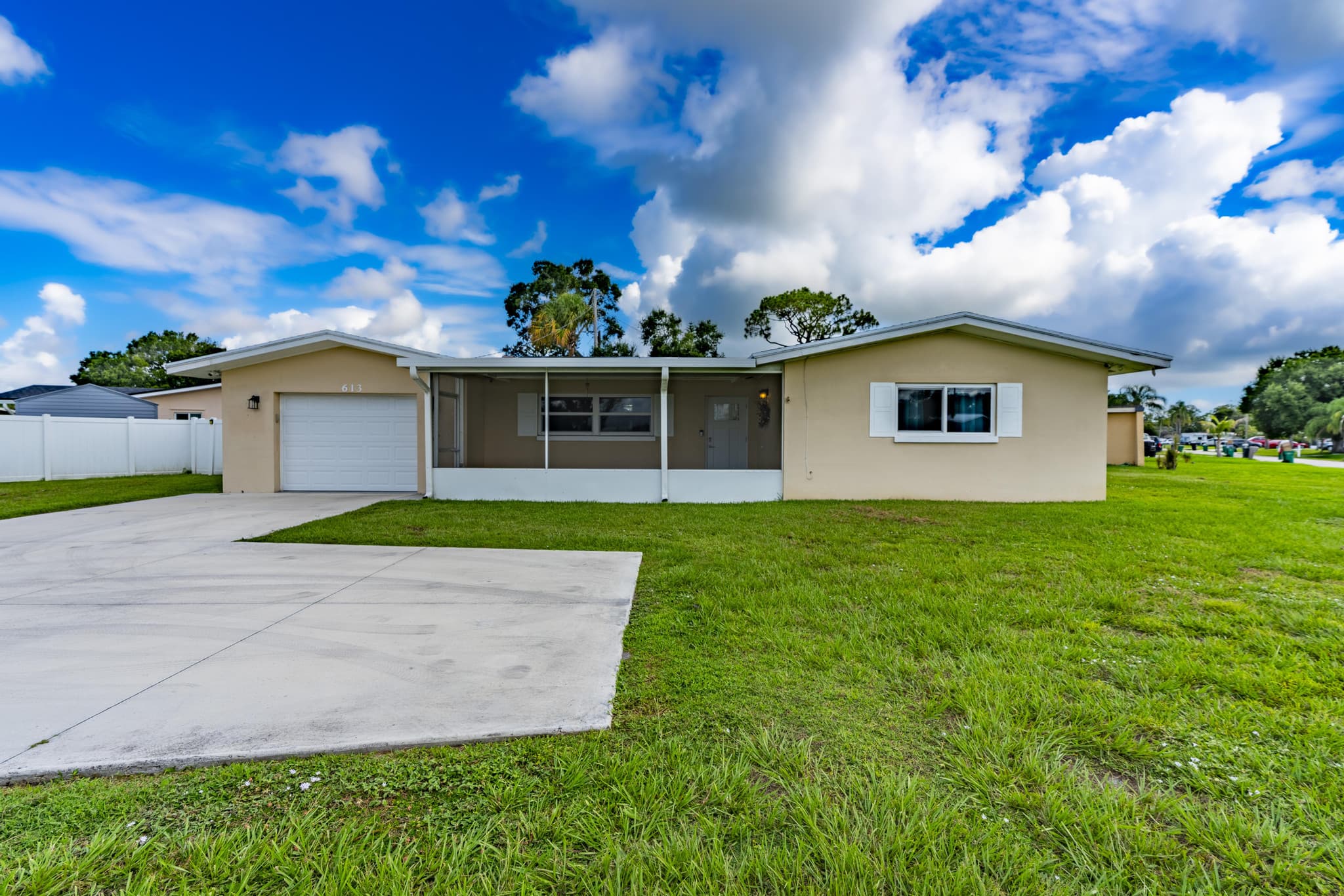 Front exterior of 613 Beach Ave under a wide Florida sky